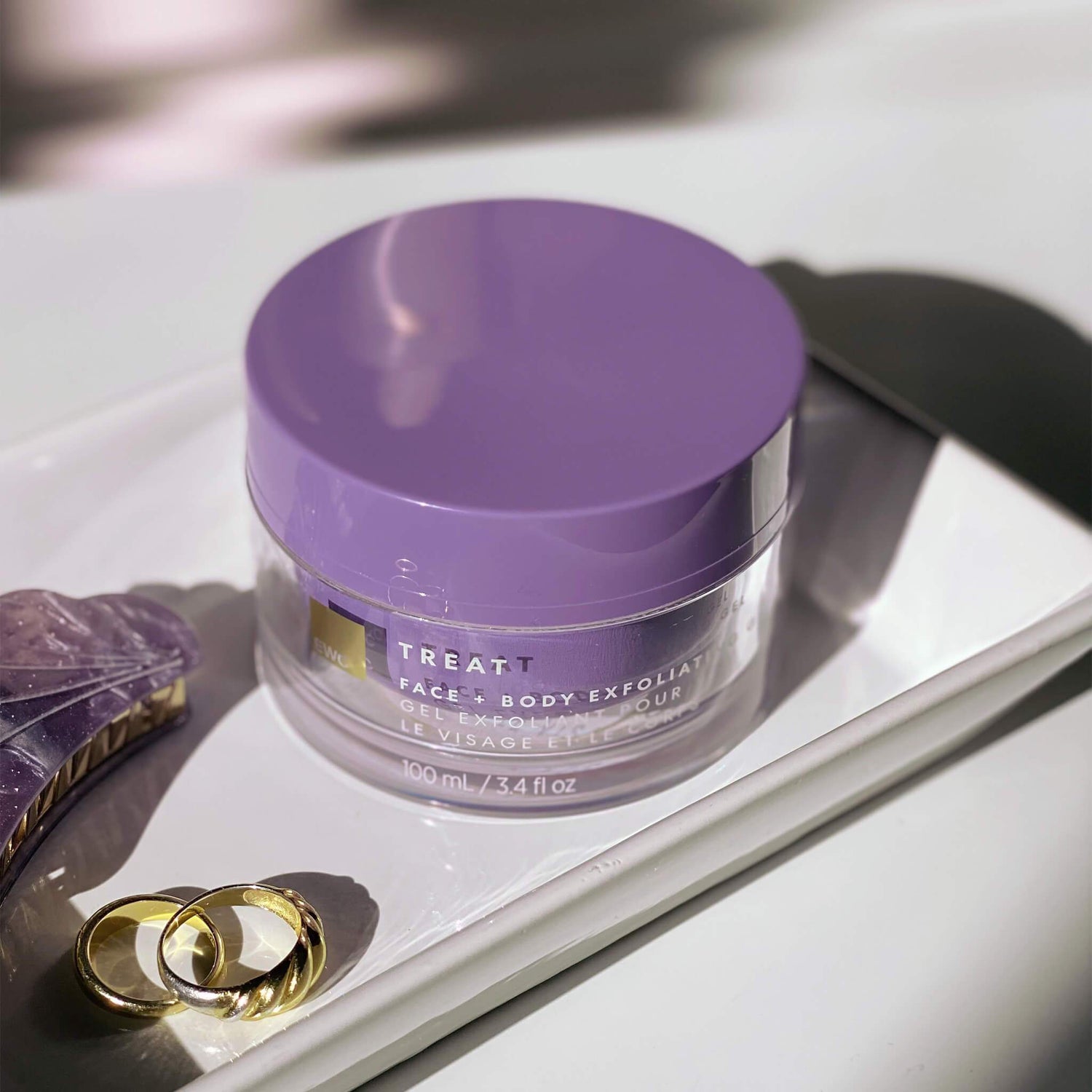 EWC TREAT Face & Body Exfoliating Gel sitting on top of a ring dish.