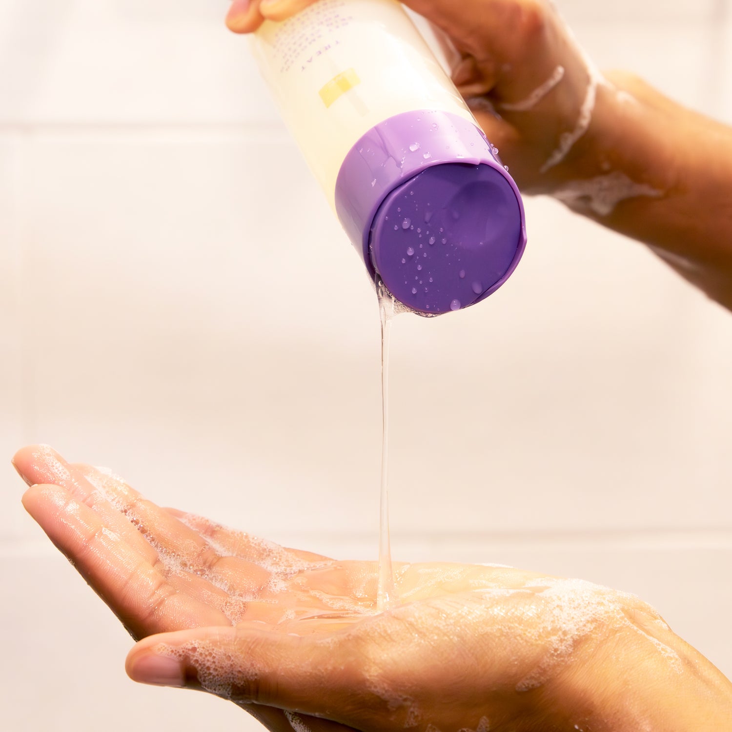 Closeup of a woman pouring the Get Smooth Skin Clearing Body Wash on her soapy hand.